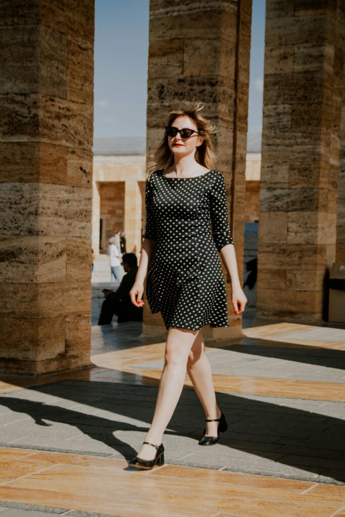 Elegant woman in a chic black dress walking stylishly in a glamorous city street fashion look