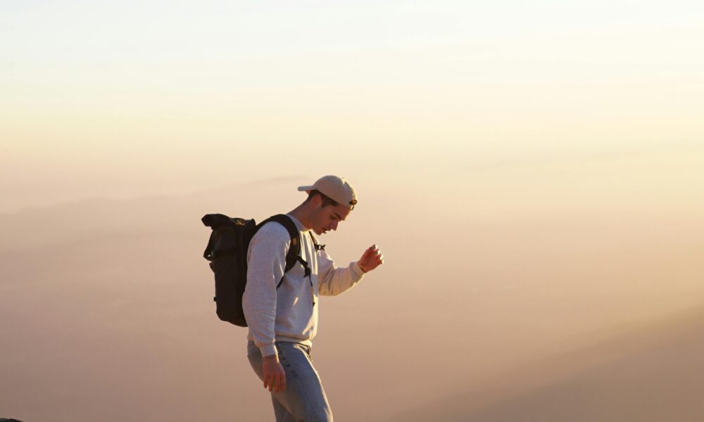 A traveler standing on a mountain peak with a backpack.