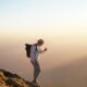 A traveler standing on a mountain peak with a backpack.