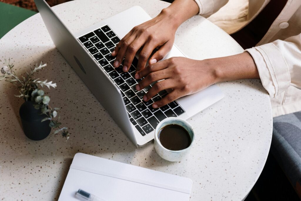 A laptop with coffee and a notebook on a tidy desk.