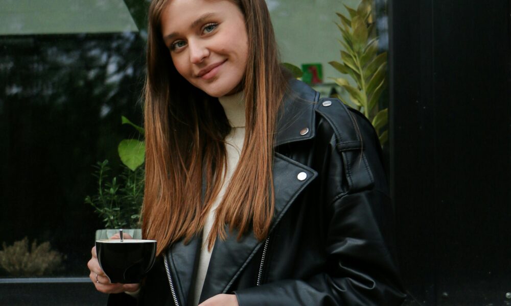 A stylish woman in jeans, blazer, and heels holding a coffee cup