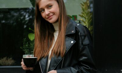 A stylish woman in jeans, blazer, and heels holding a coffee cup