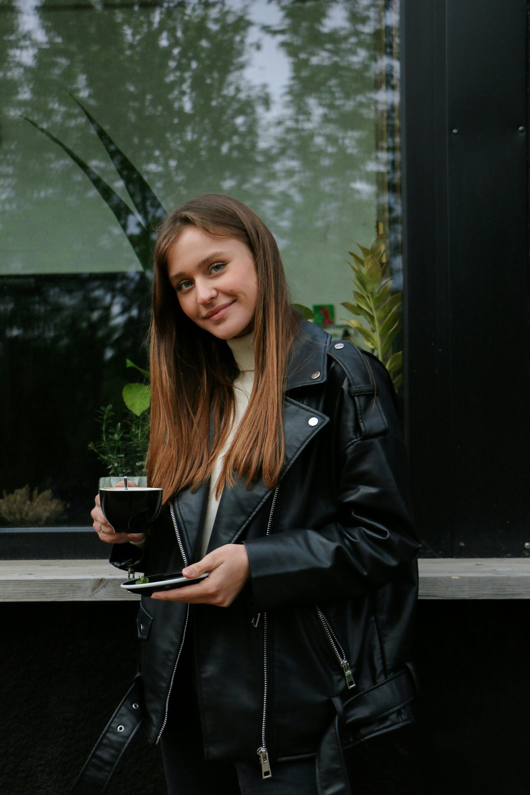 A stylish woman in jeans, blazer, and heels holding a coffee cup
