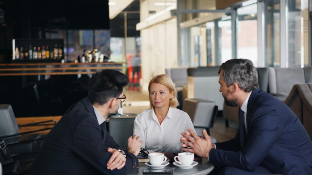 A woman in white suits at a corporate meeting table.