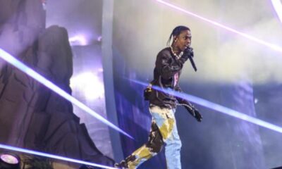 Travis Scott performing under vibrant lighting.