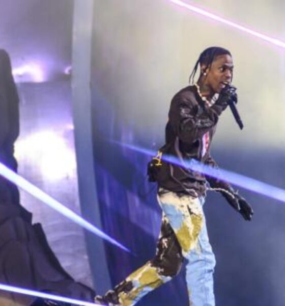 Travis Scott performing under vibrant lighting.