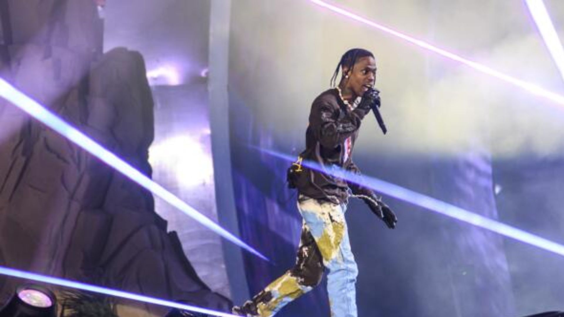 Travis Scott performing under vibrant lighting.