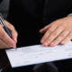 A picture showing a person signing a check.