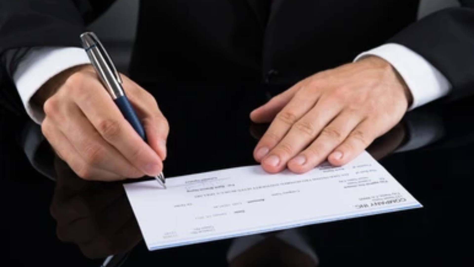 A picture showing a person signing a check.