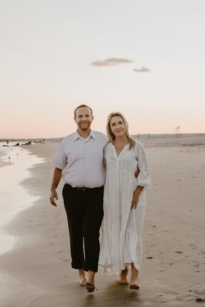 Couple walking along the shore during sunset.