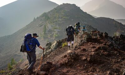 A stunning mountain landscape with hikers trekking on a trail at sunrise.