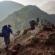 A stunning mountain landscape with hikers trekking on a trail at sunrise.