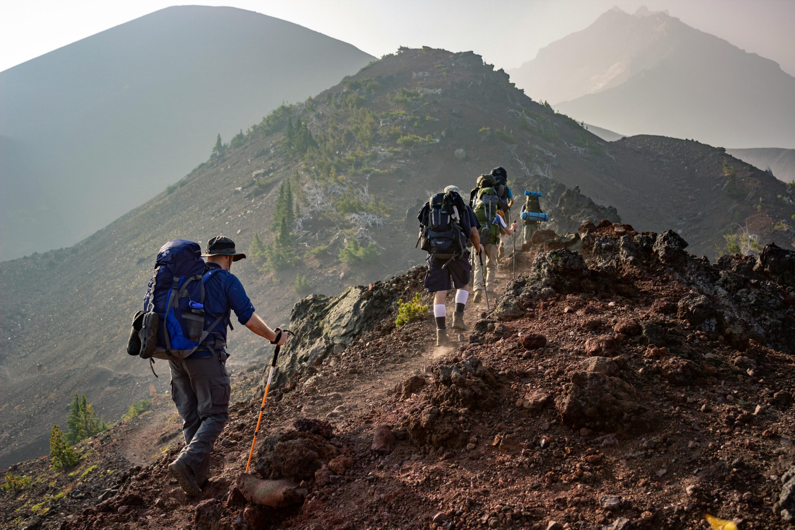 A stunning mountain landscape with hikers trekking on a trail at sunrise.